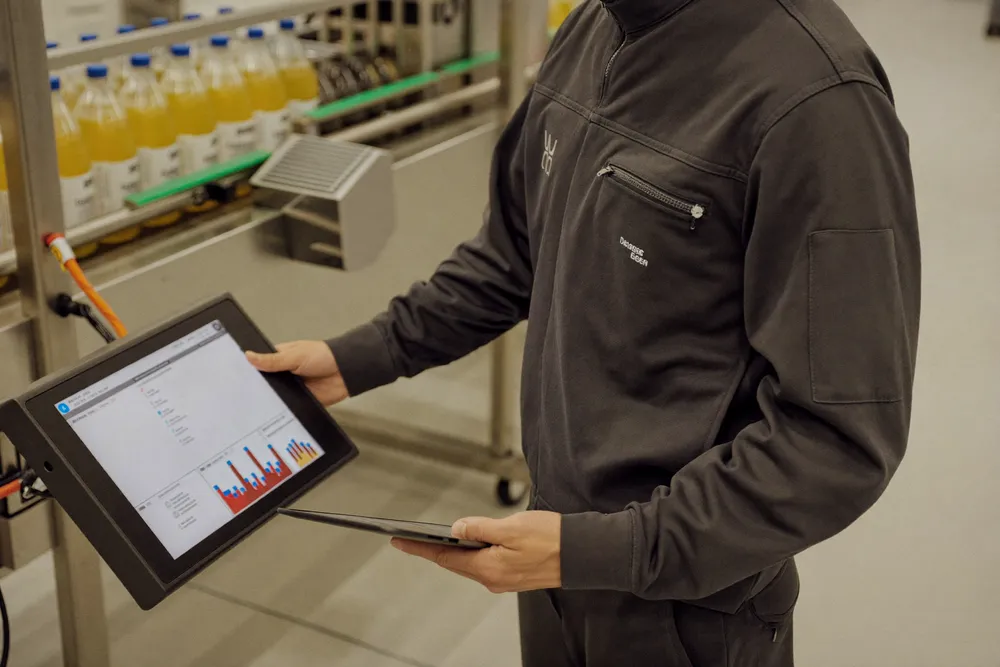 A service engineer with a tablet at a machine panel